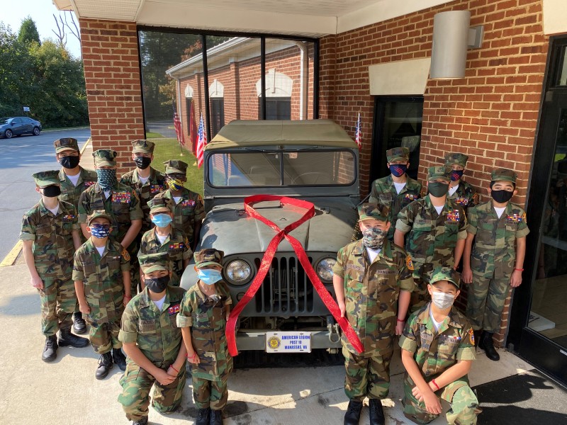 Youth members of Manassas Young Marines around a military jeep